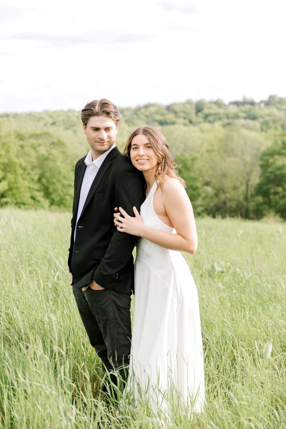 Engaged couple walking hand-in-hand through the tall grass at Natirar Park in Peapack, NJ.