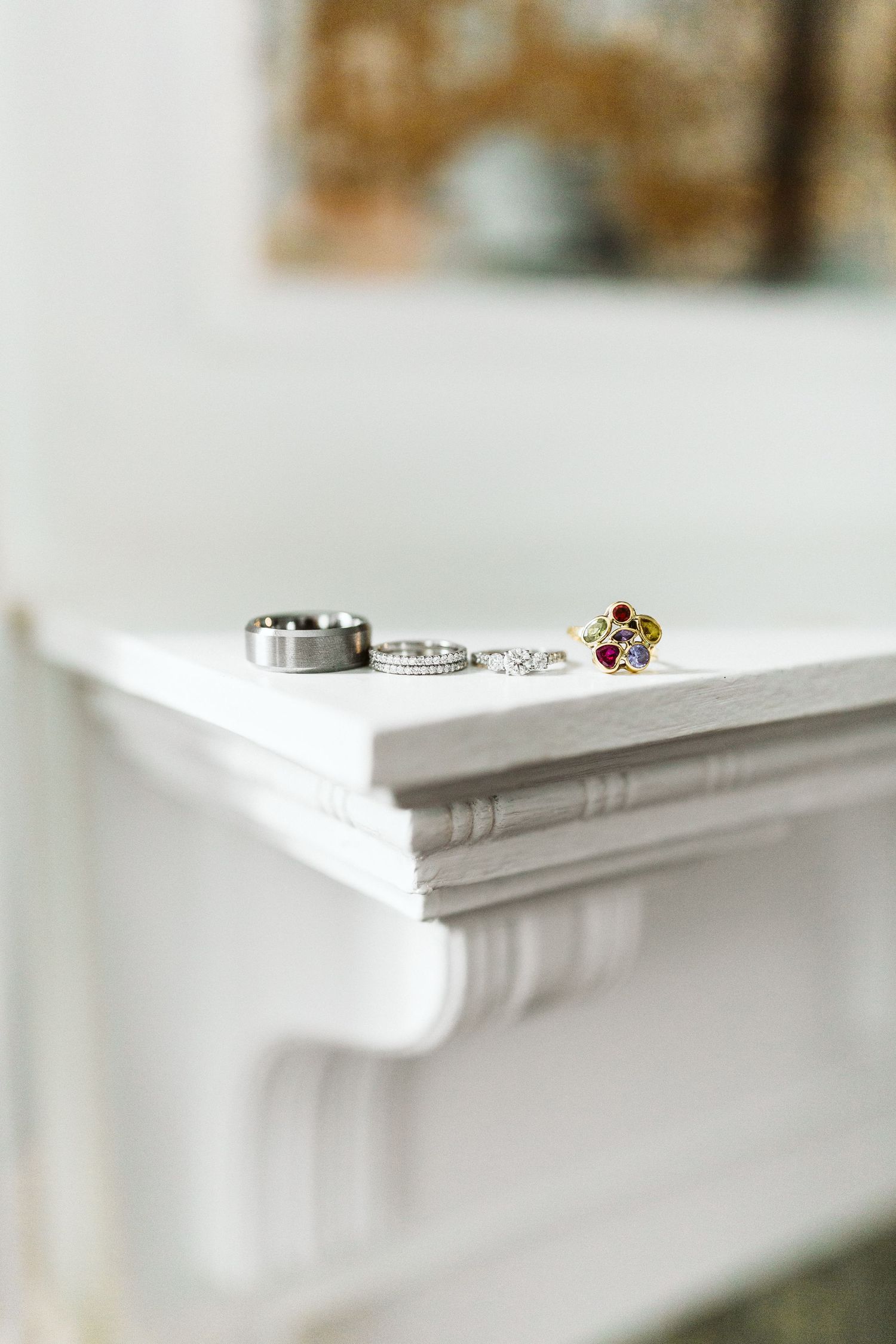 Wedding rings and jewelry arranged on white surface in soft natural light.