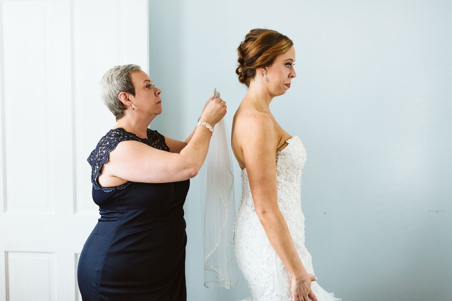 A bride and woman in navy share an emotional moment before the wedding ceremony.