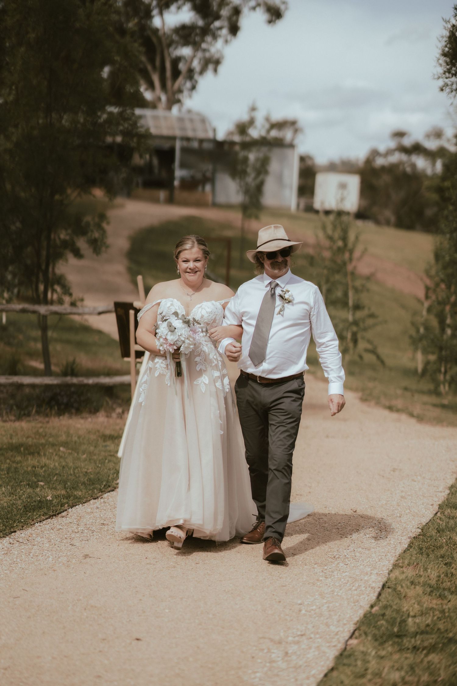 A couple walking together on a garden path during their rustic outdoor wedding ceremony.
