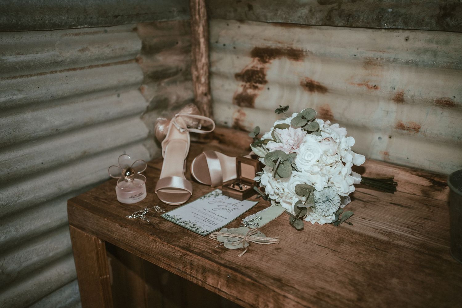 Rustic wooden table settings with white floral arrangements create a romantic ambiance in a cozy barn venue.
