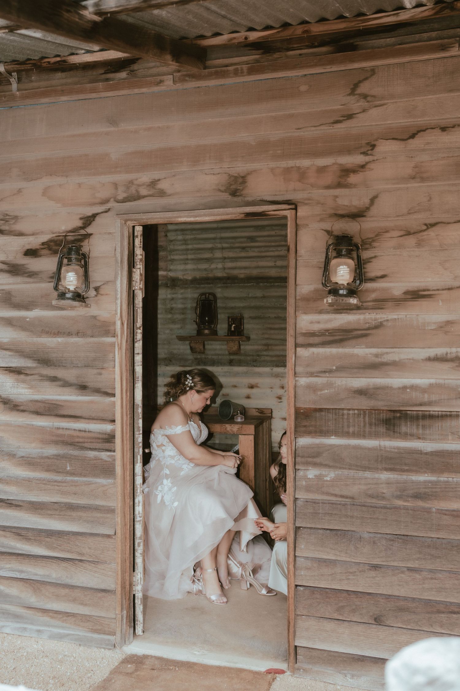 A rustic wooden cabin doorway with vintage lanterns is framed by weathered logs and a worn entrance.