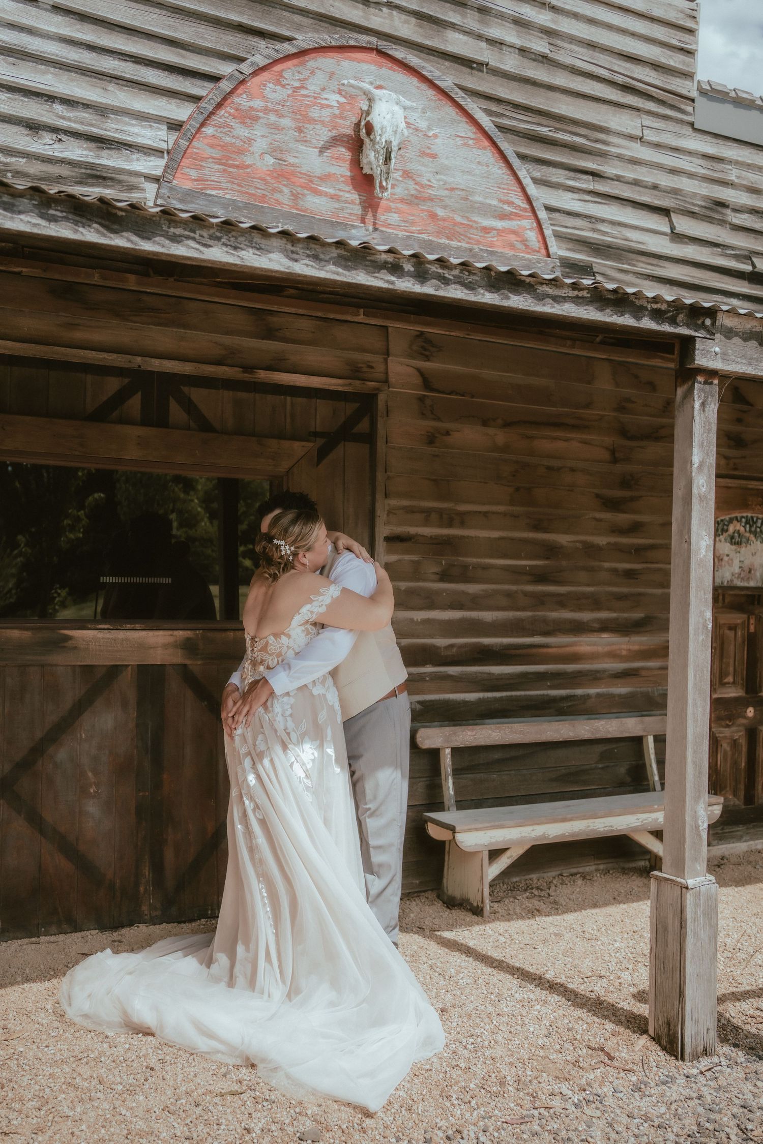An emotional first look moment outside a rustic barn venue creates a heartfelt scene.