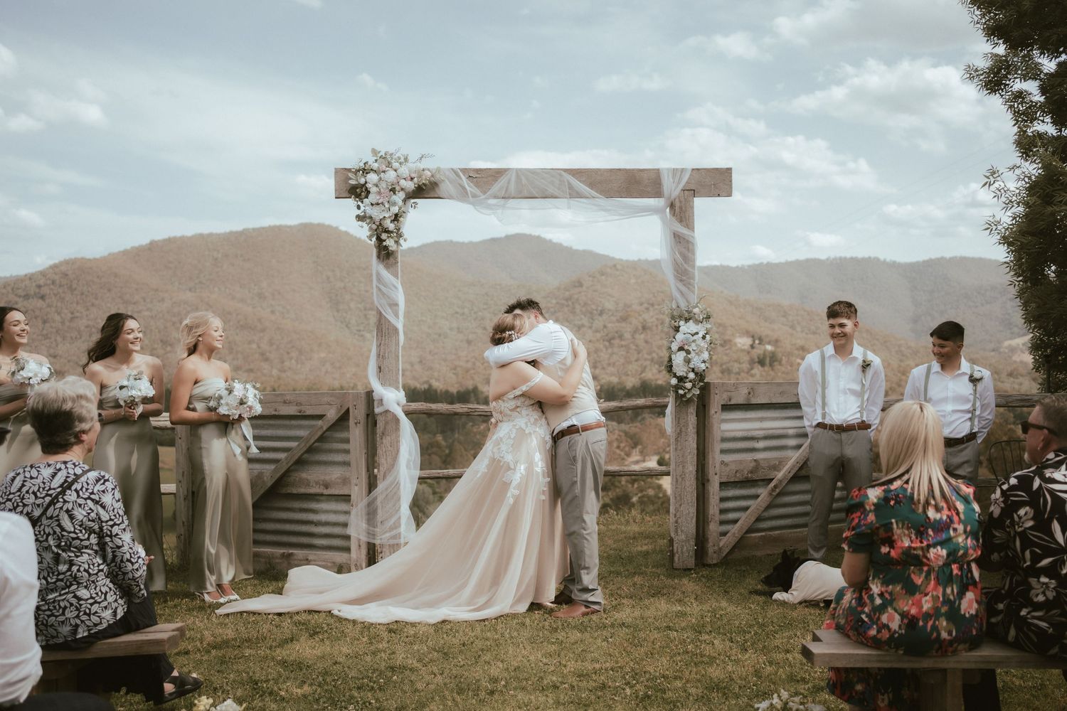 Wedding ceremony surrounded by desert mountains with rustic wooden fencing and pink floral arrangements.