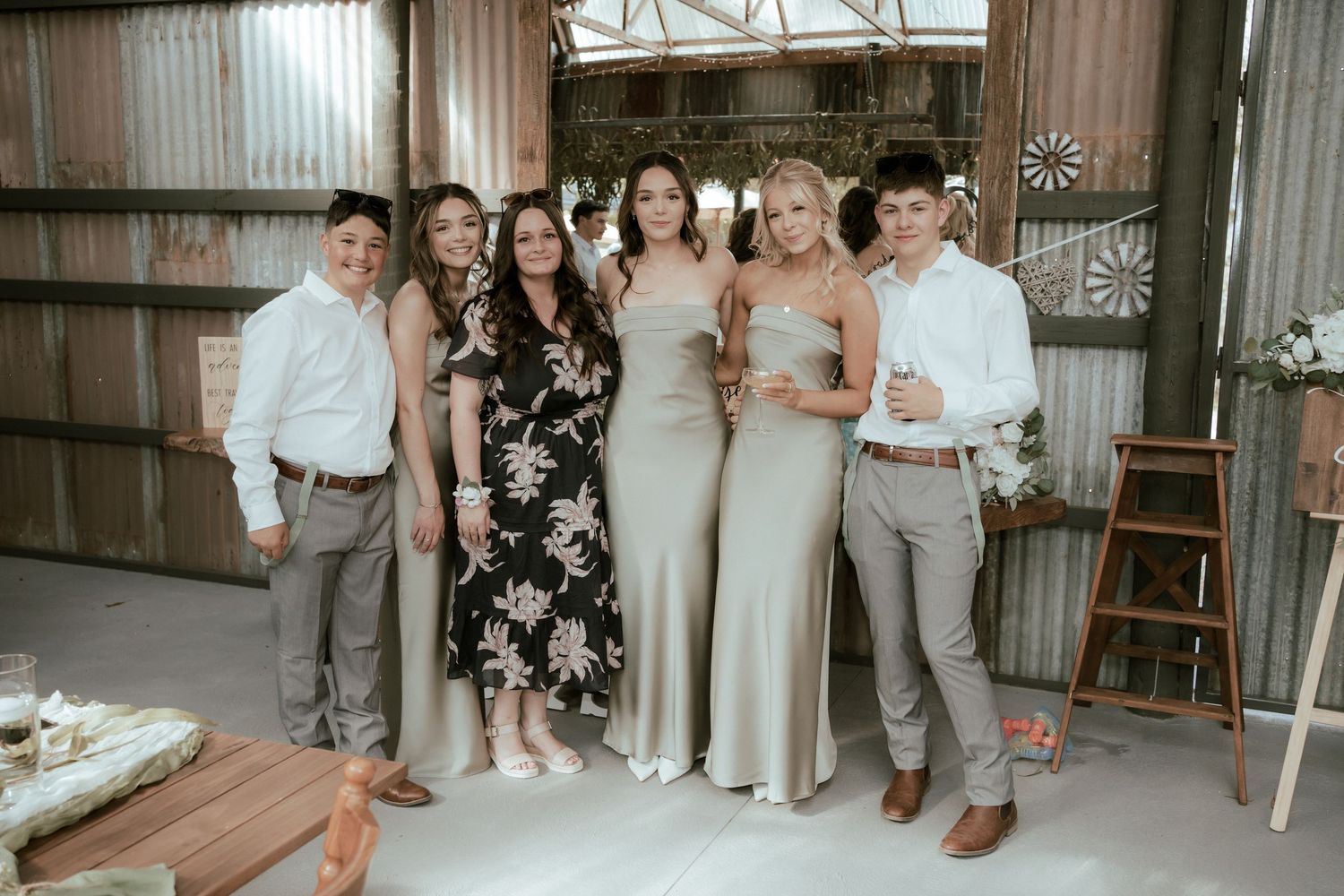Wedding party gathered together in a rustic barn setting with natural lighting and simple decor.