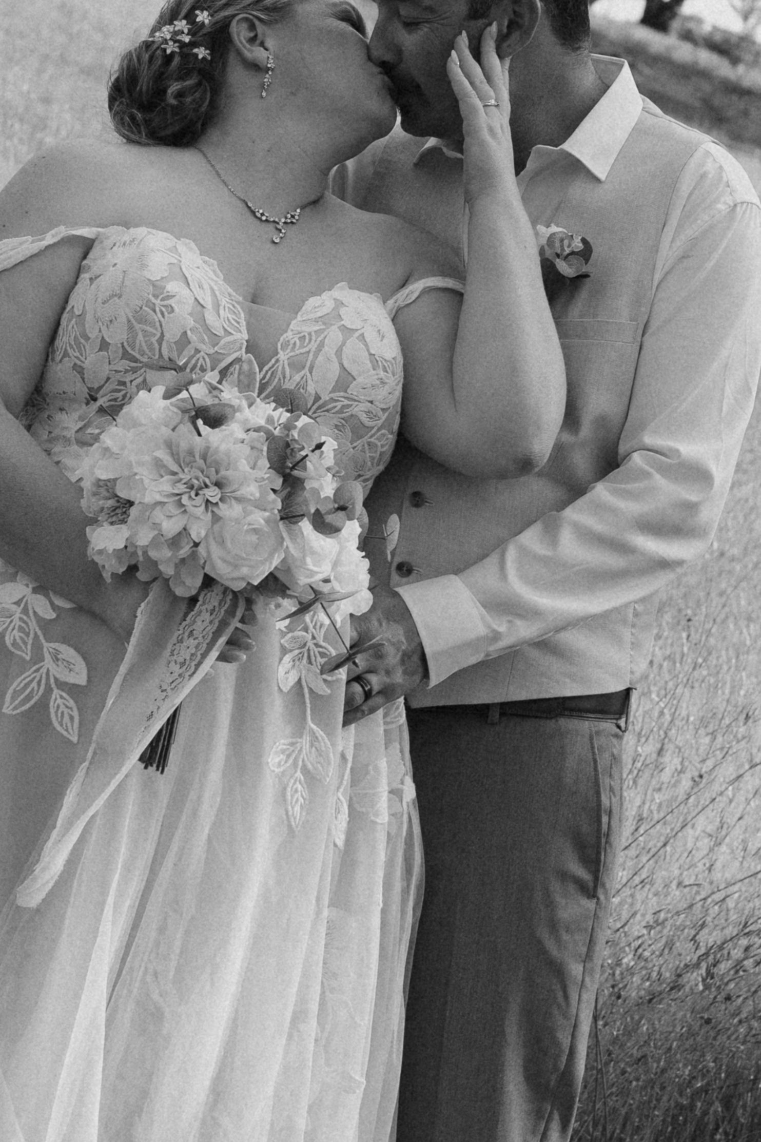 A romantic black and white wedding photo showing a tender moment, with the bride holding a beautiful bouquet.