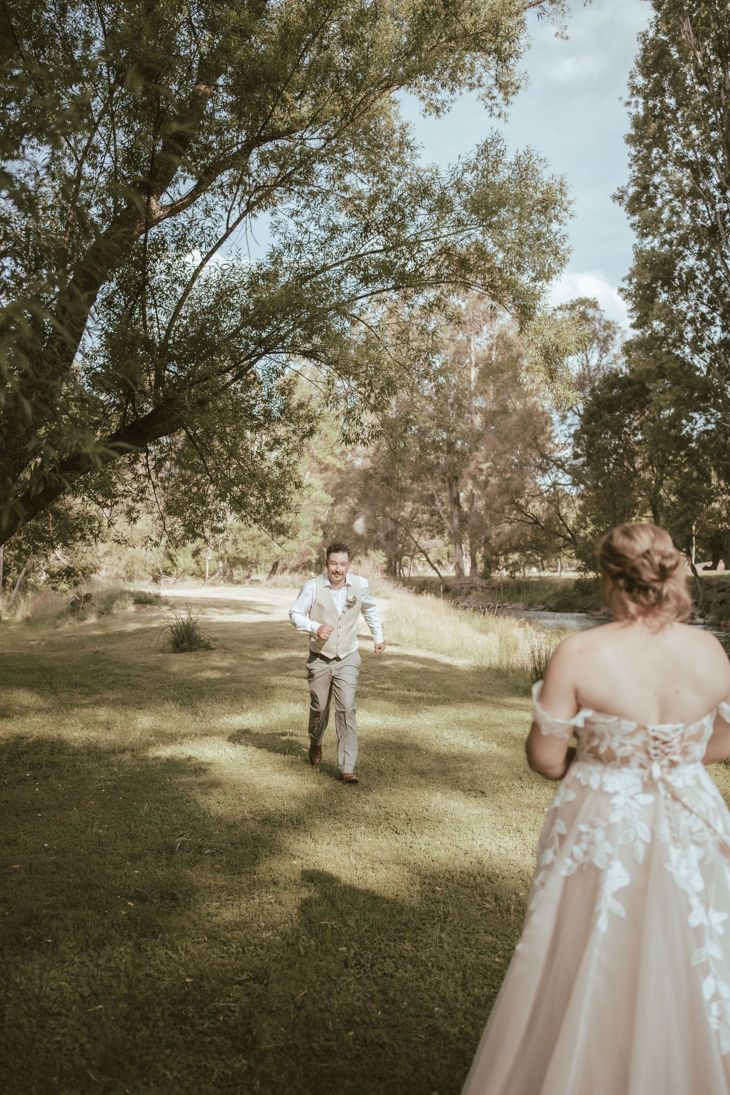 A romantic wedding scene in a sun-dappled woodland with a couple in formal attire.