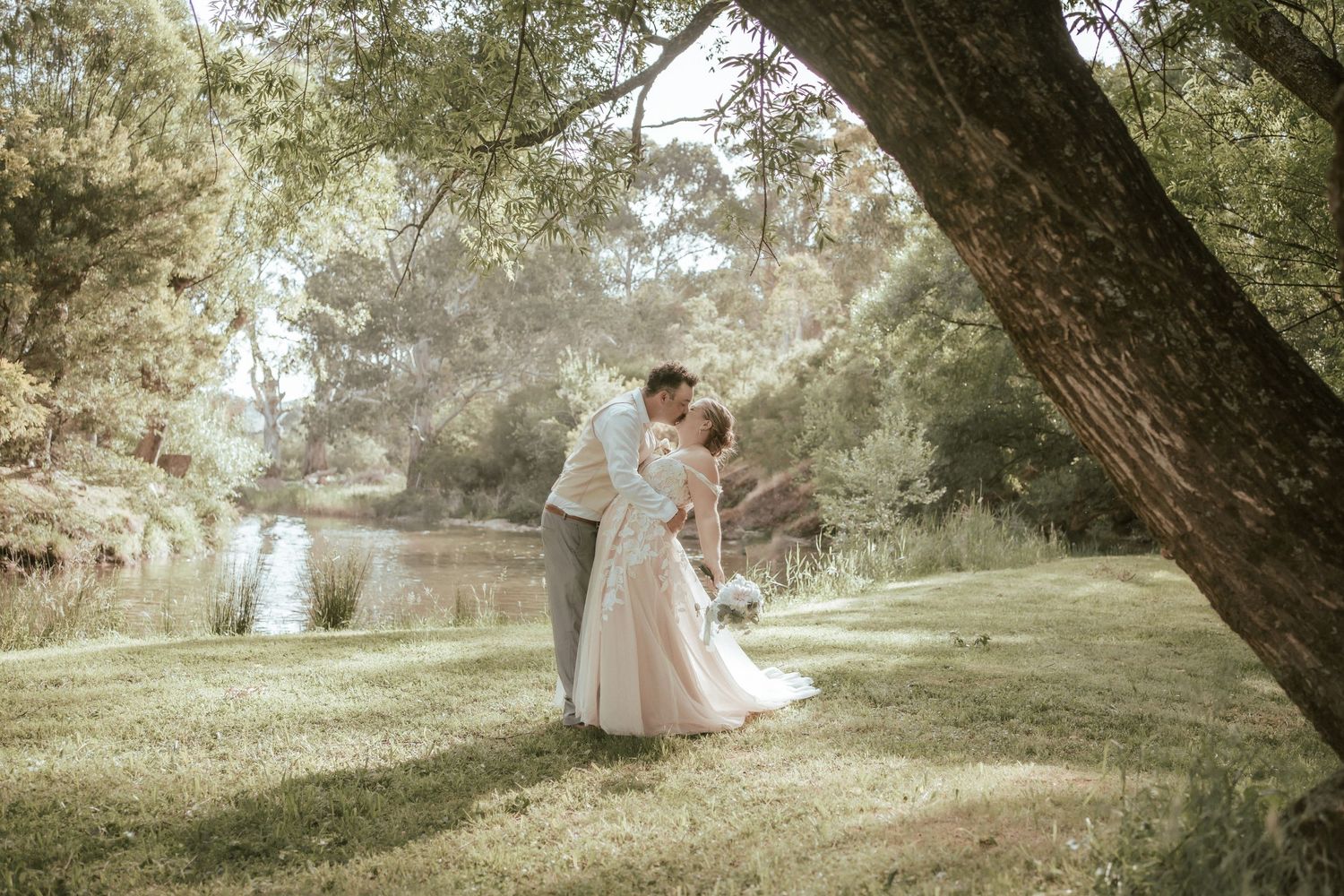 Dreamy outdoor wedding photography with a billowing off-shoulder dress beneath arching tree branches.