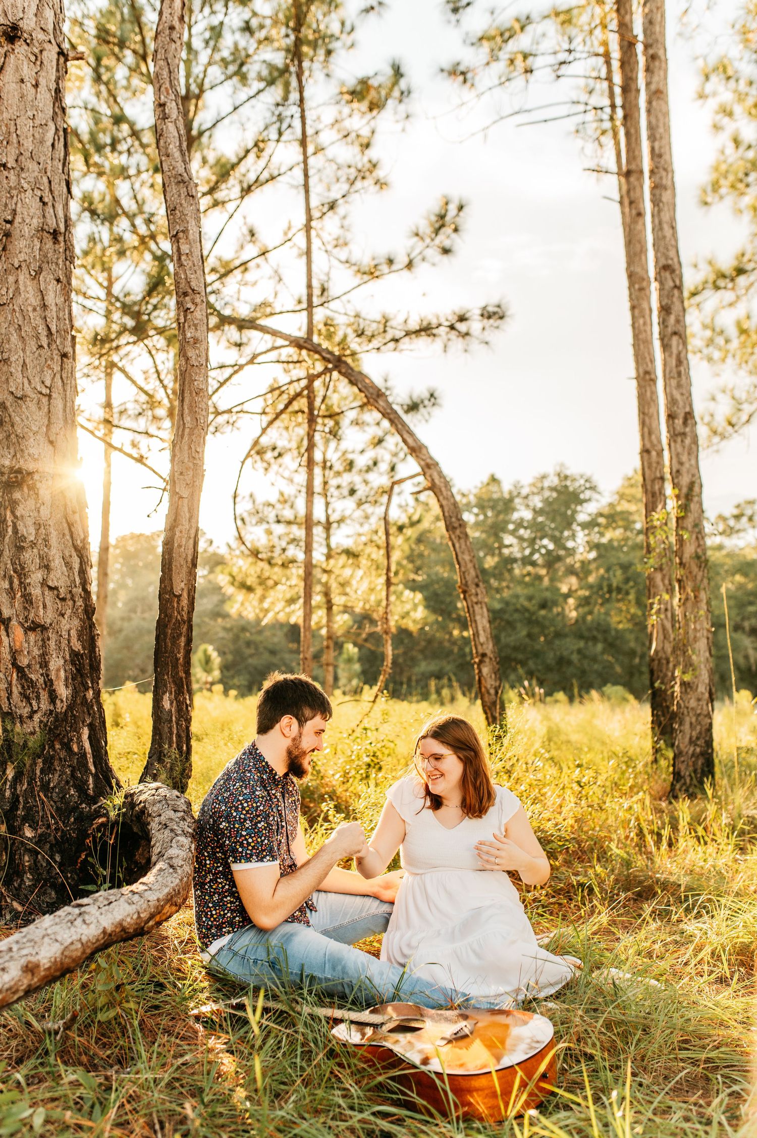A couple enjoying a sunset picnic among tall pine trees.