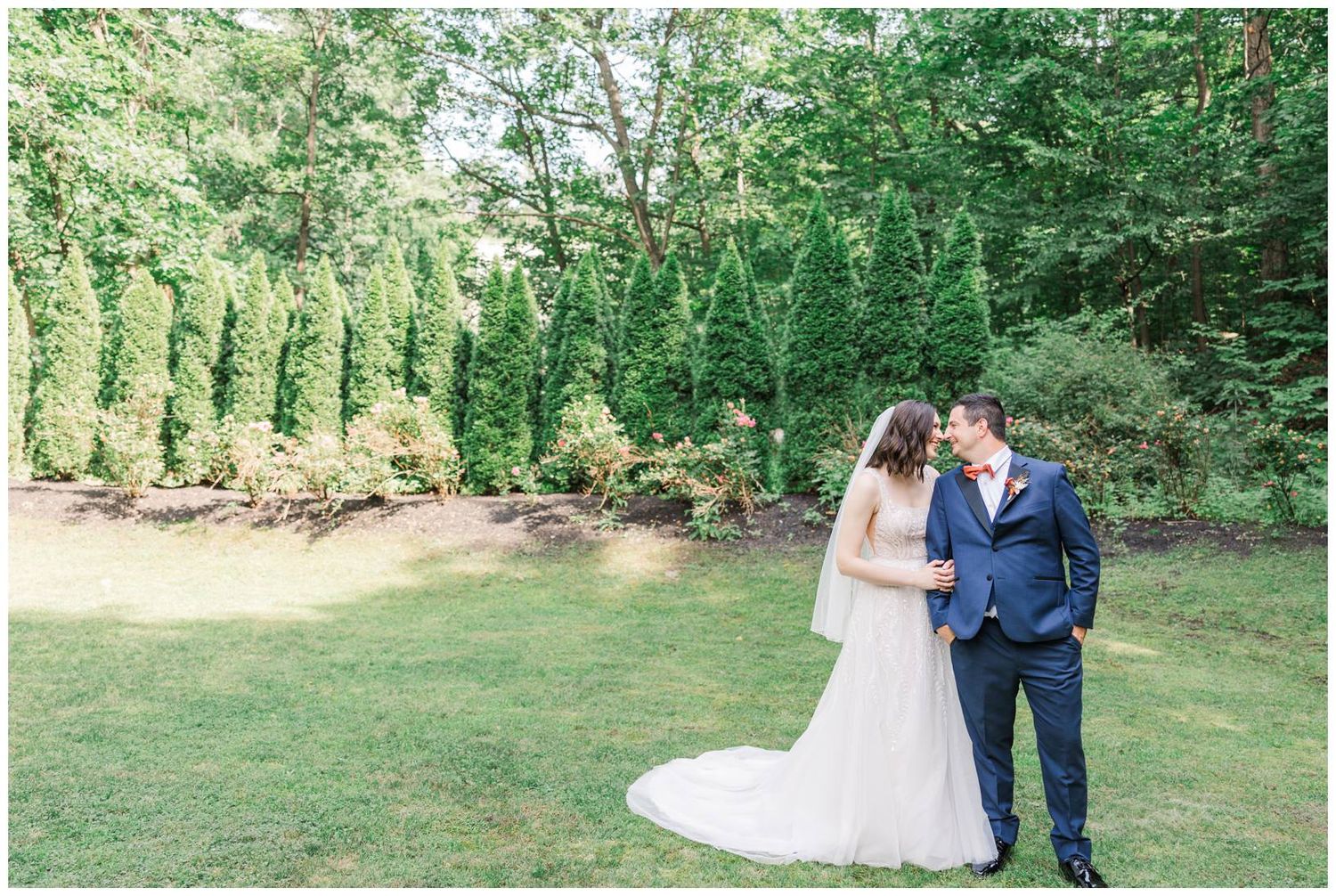Rustic outdoor wedding ceremony with bride and groom surrounded by lush greenery and natural lighting.