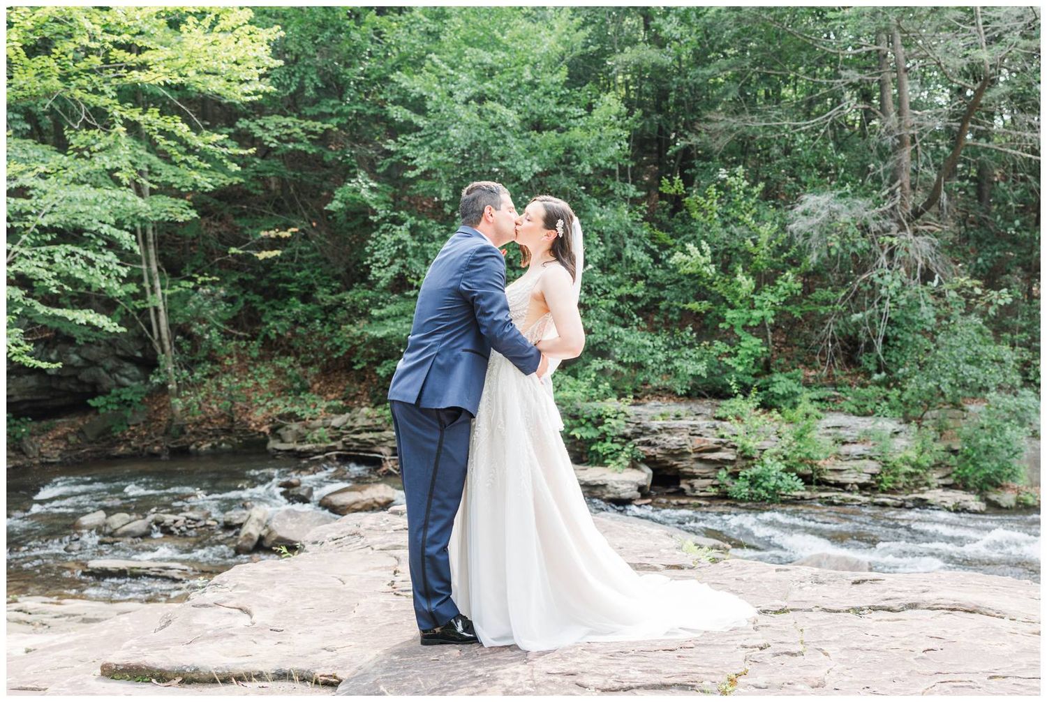 Outdoor wedding portraits in lush green forest setting with natural stone features.