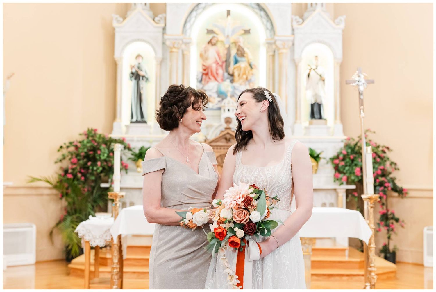 Bridal party in navy and coral attire posing for formal photos inside ornate Catholic church.