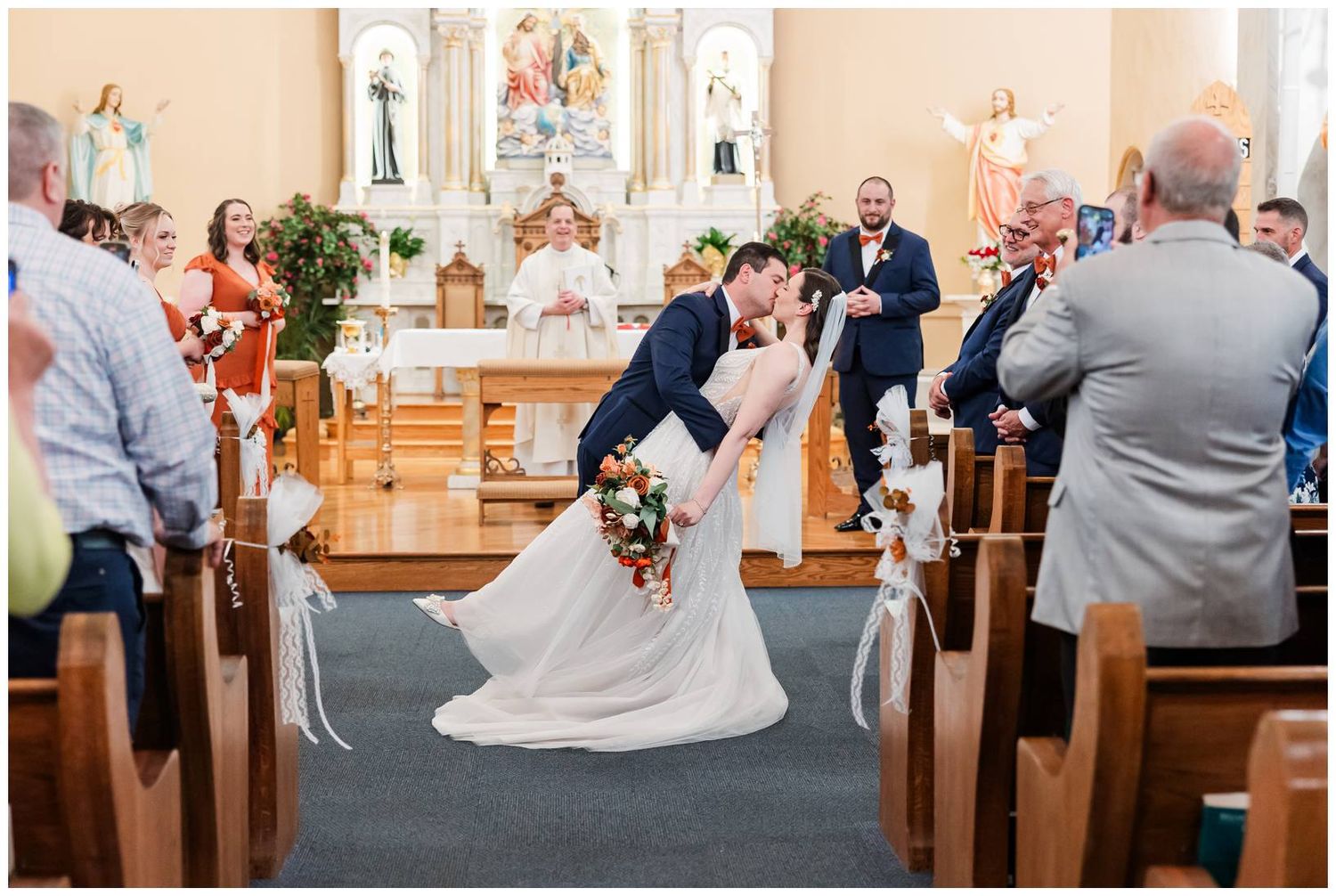 Wedding ceremony in progress at traditional Catholic church with wooden pews.