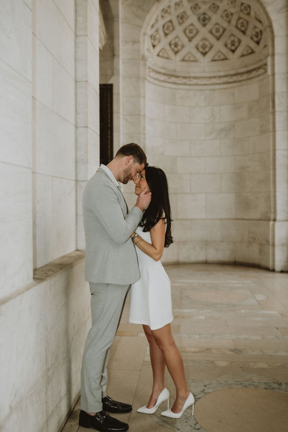 A romantic moment between a couple in formal attire standing beneath an ornate domed alcove.