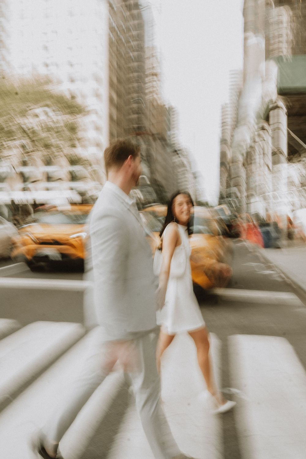 A dreamy motion-blur photo of a couple on city steps with yellow taxis in background.