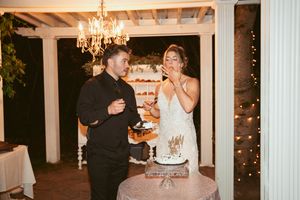 Wedding couple sharing a joyful moment while cutting their wedding cake under an elegant chandelier.
