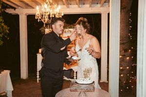 A couple shares a fun moment while cutting their wedding cake under a crystal chandelier.