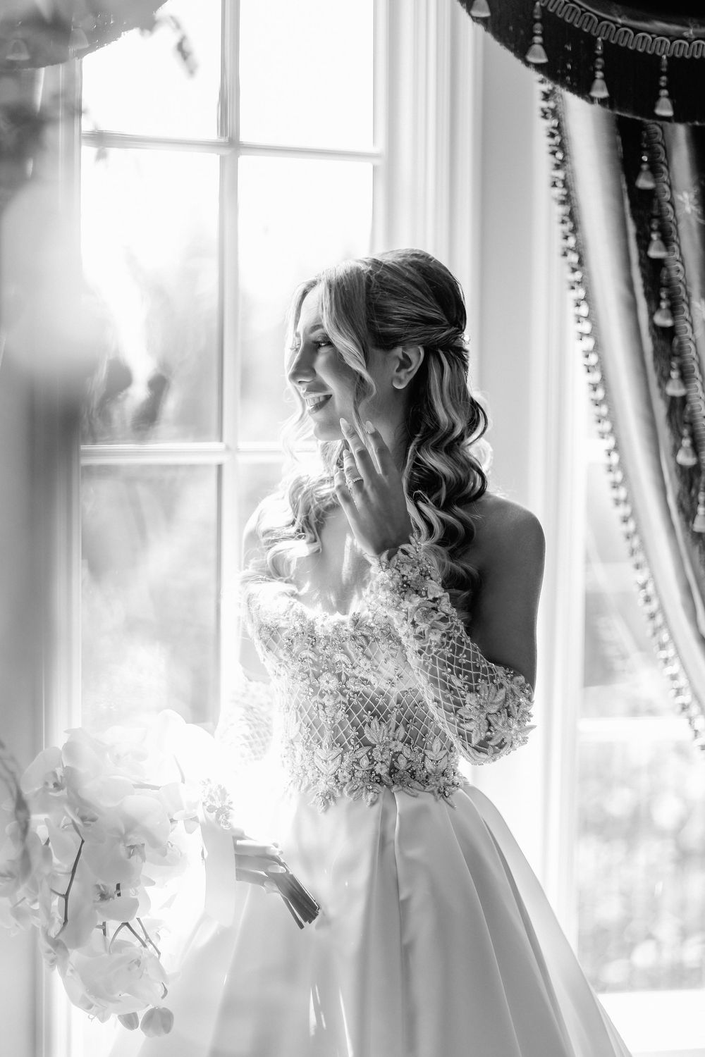 Ethereal black and white photographs show a bride in delicate lace gown by sunlit windows creating dreamy bridal portraits.