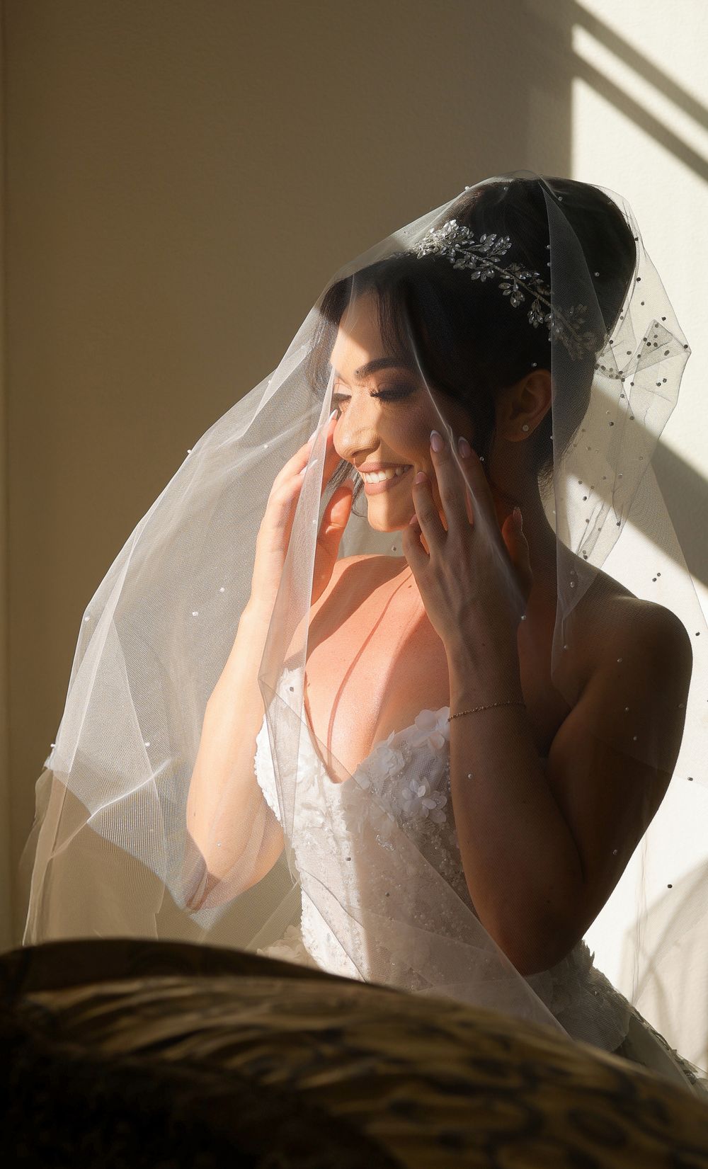 A bride in a white wedding dress and veil sits in dramatic window light creating a series of moody portraits.