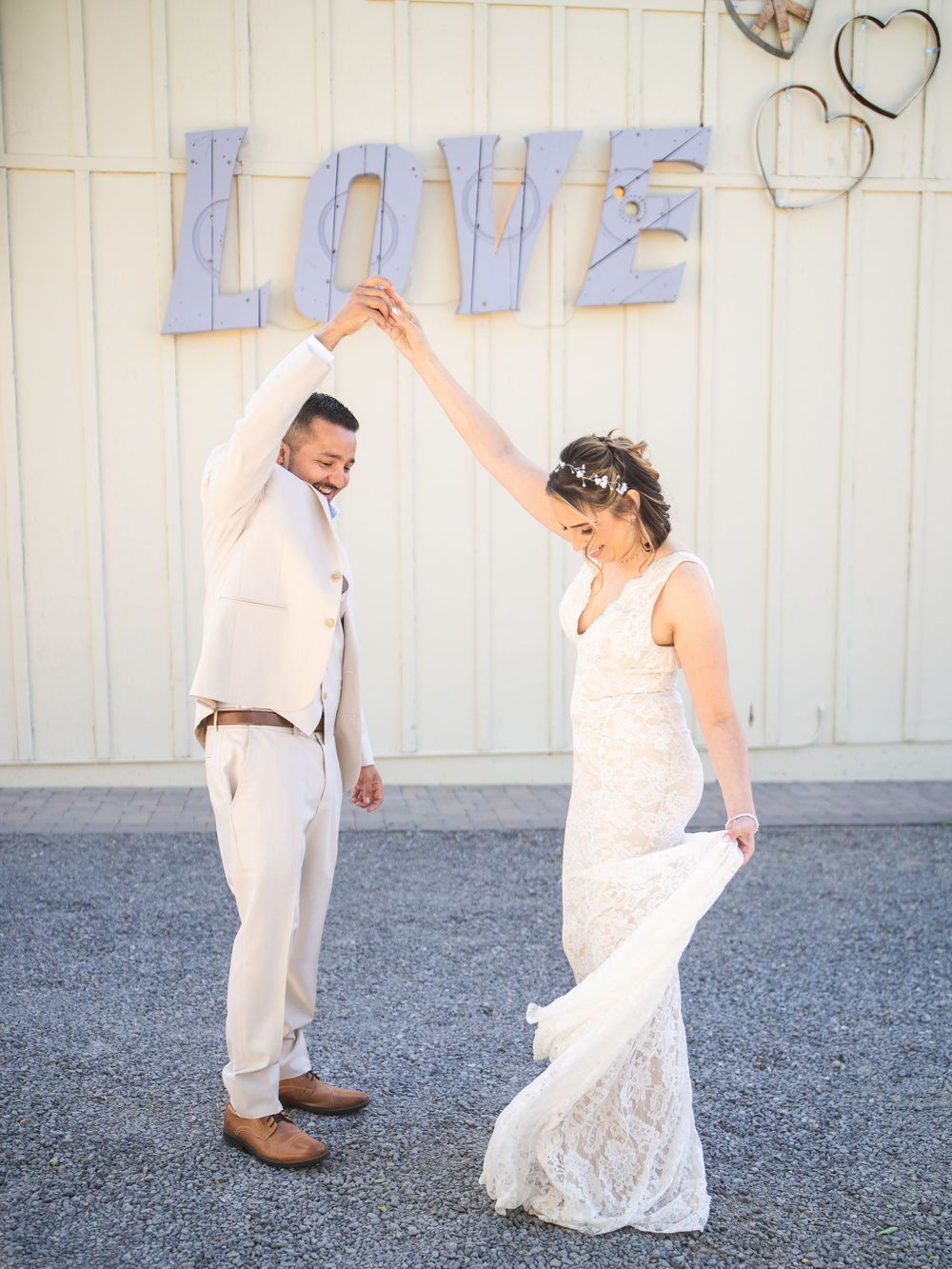 A sweet series of five wedding photos showing a couple in white attire dancing and twirling together on a gravel surface.