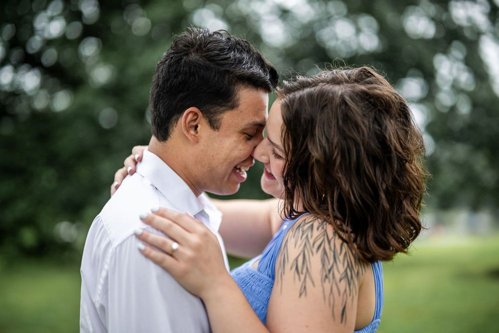 Romantic couple share an intimate moment in a beautiful garden setting with blurred green foliage background.