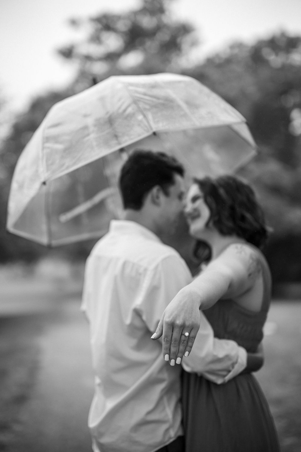 A romantic black and white photo series showing a couple kissing under a white umbrella in an outdoor setting.