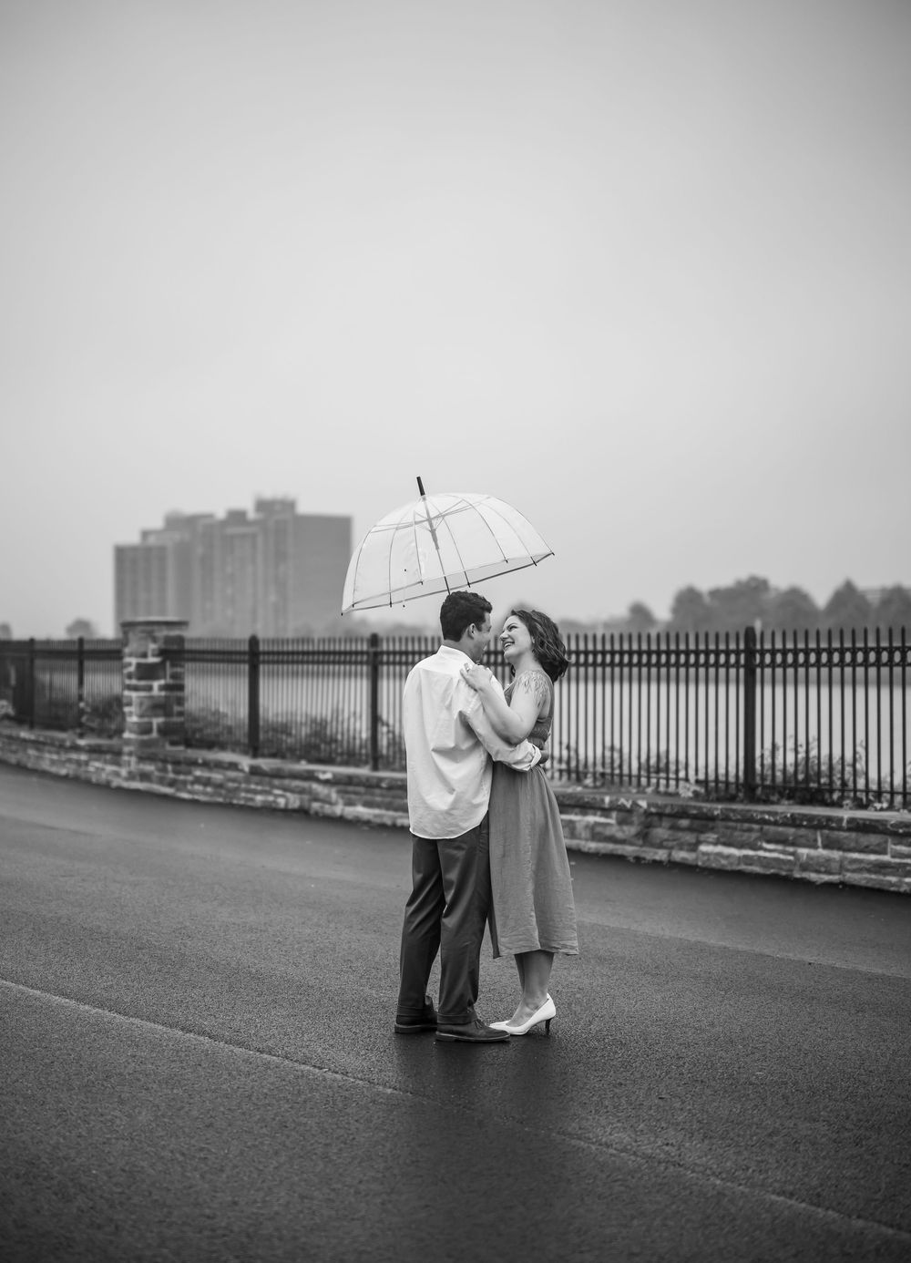 Black and white photo sequence of couple sharing intimate moments under an umbrella on an overcast day.