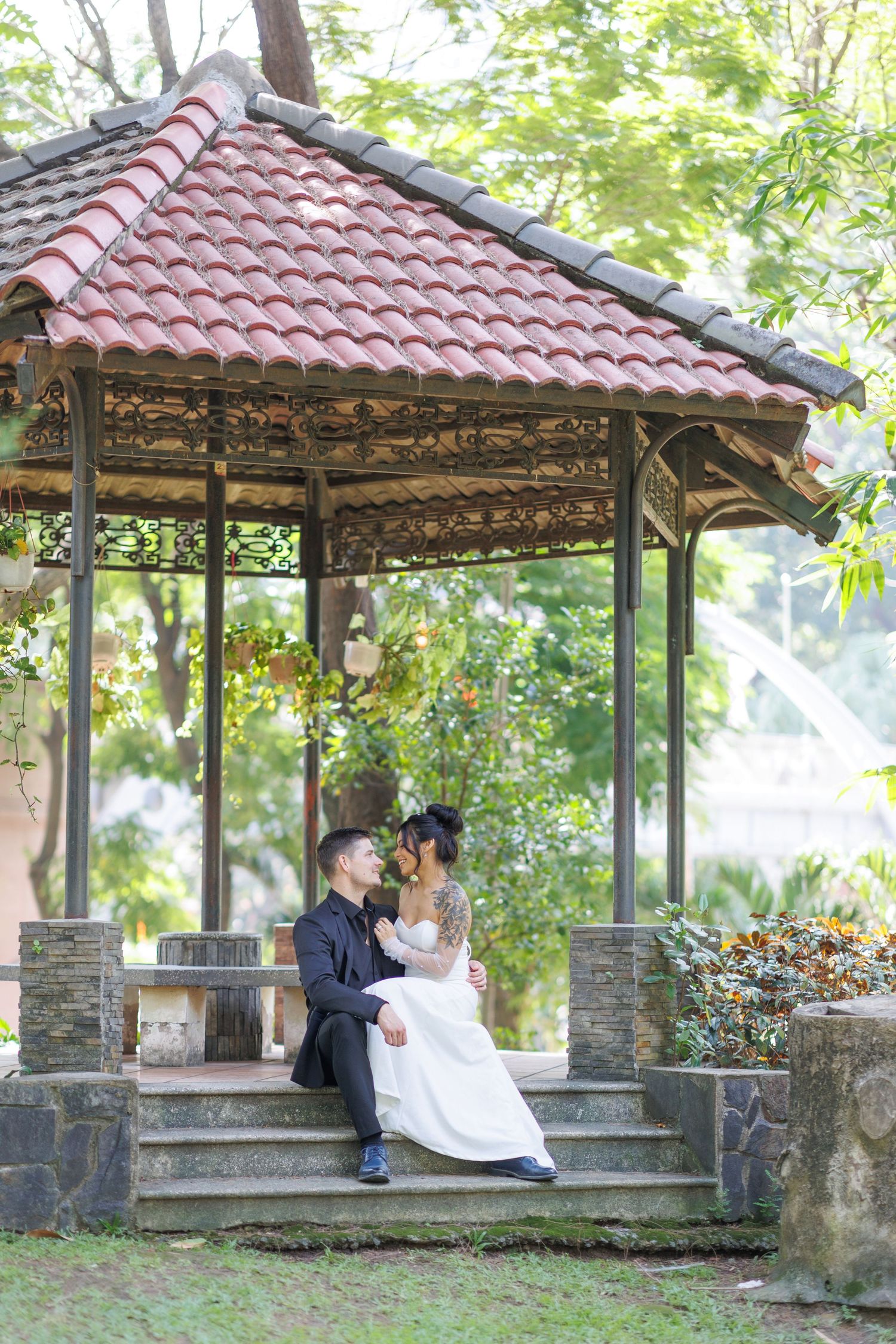 Wedding portraits under a stone gazebo with red tile roof and ornate details.