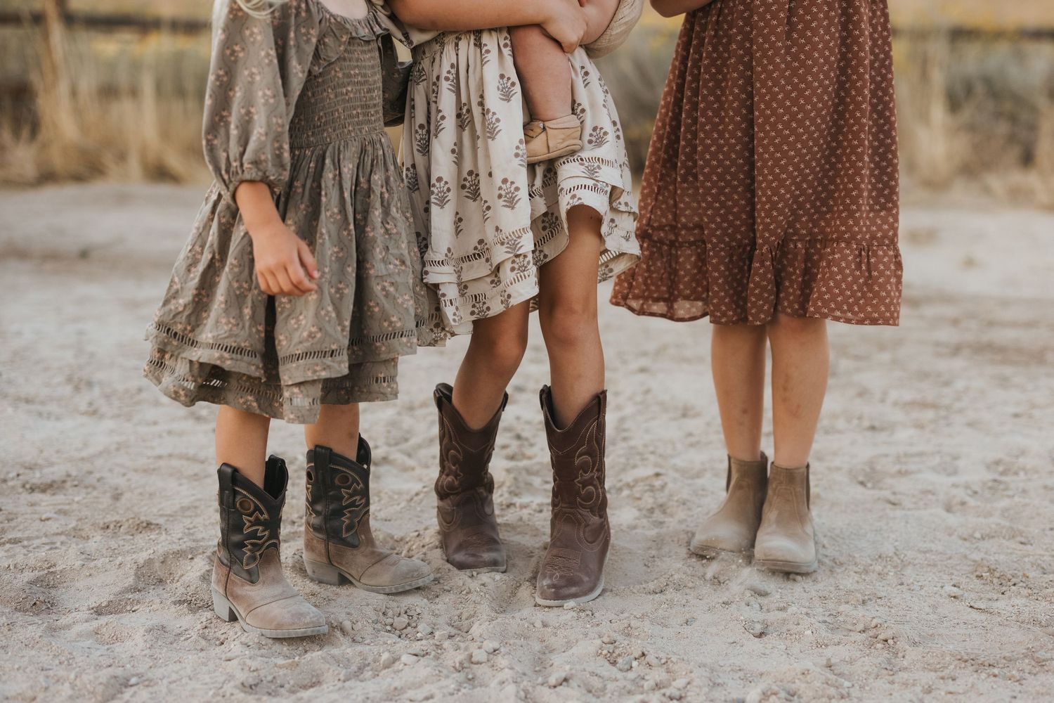 A family with three children walks together in a sun-drenched field during golden hour, creating a warm outdoor portrait.