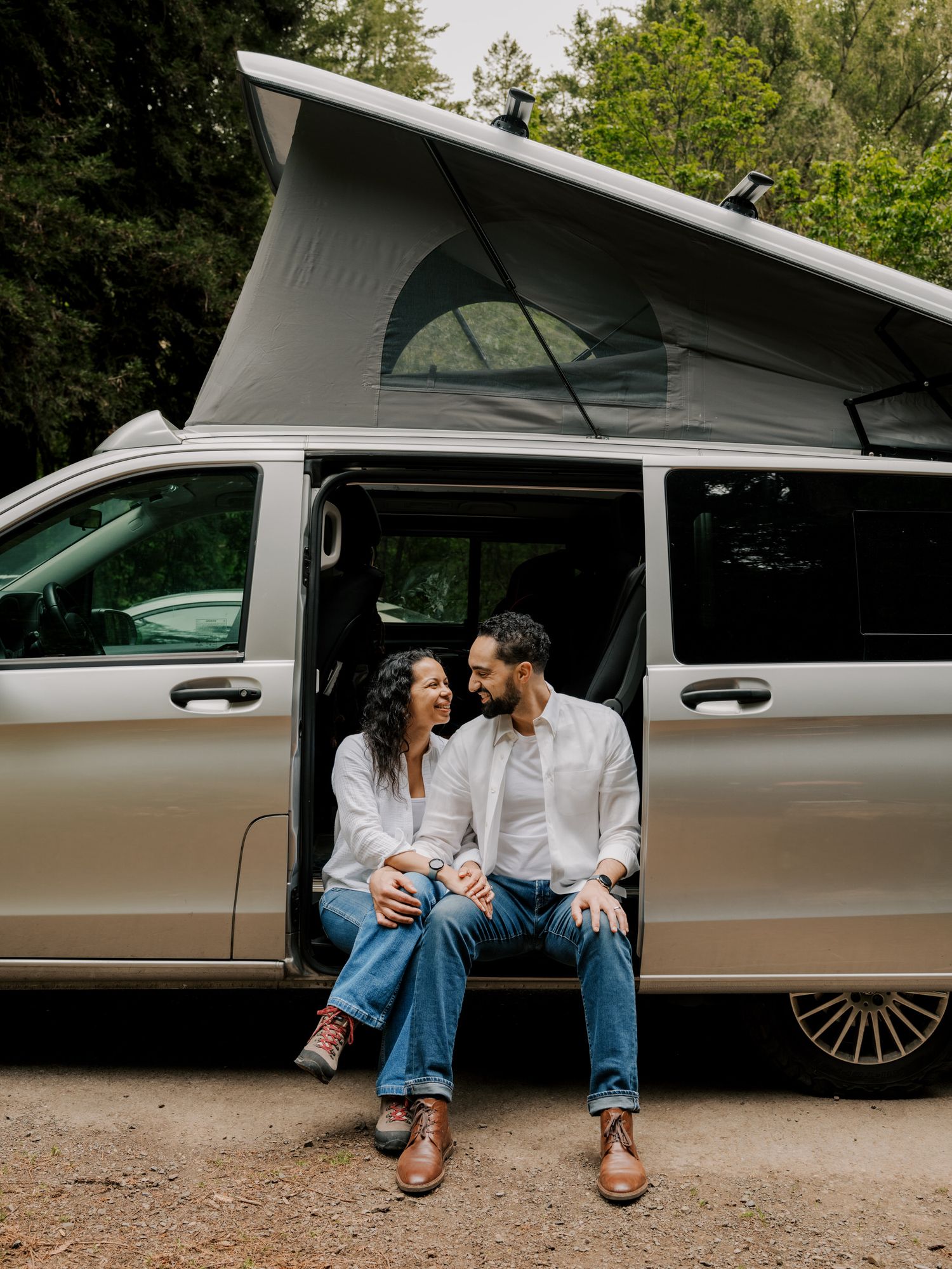 A couple sits together on a bench beside a sleek limousine for what appears to be an intimate outdoor photography session.