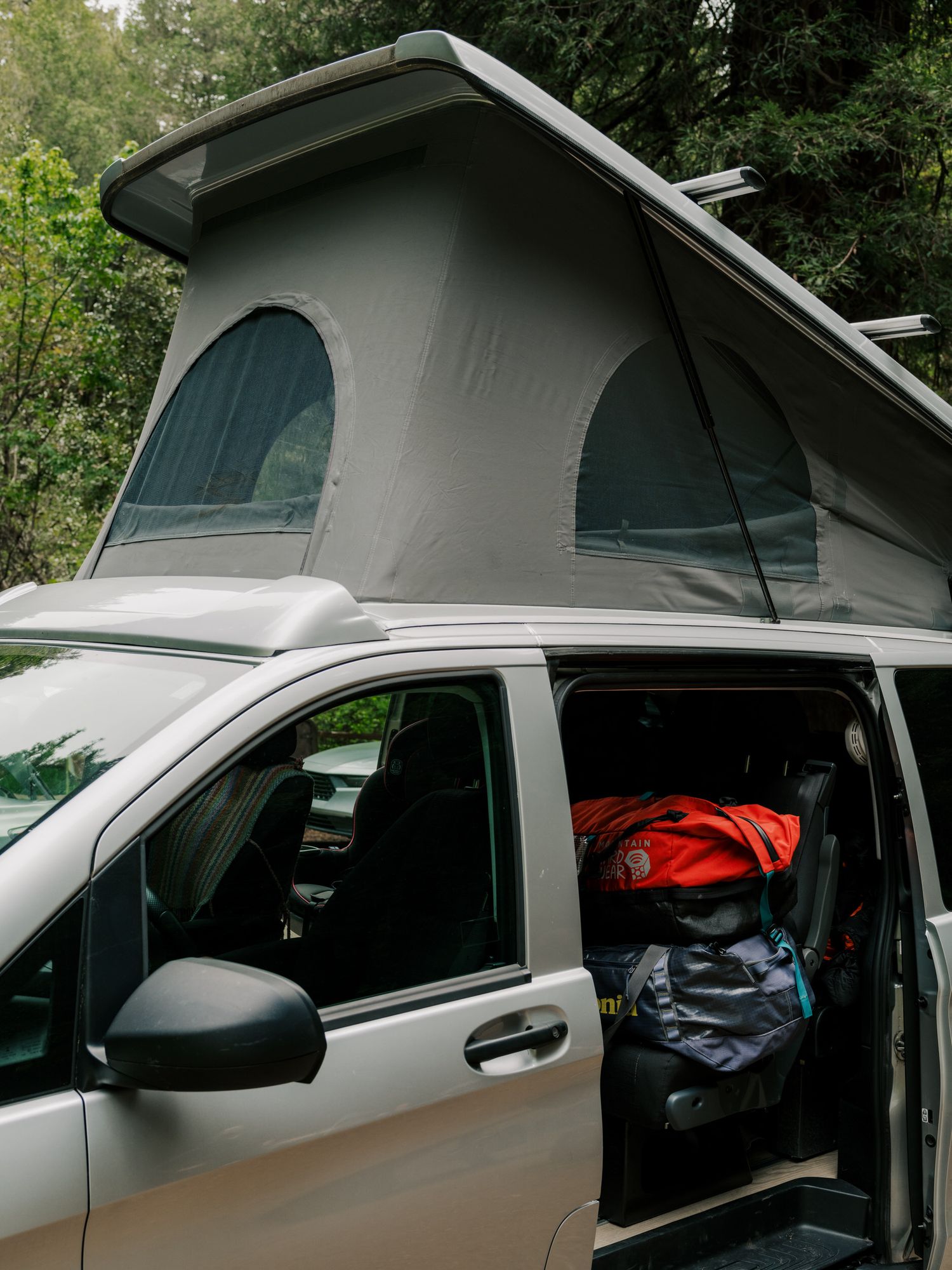 A white camper van with a pop-up roof shows the progressive stages of its roof extension in a five-image sequence.