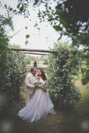 A bride and groom in a flower garden looking at each other