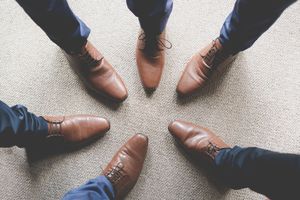 A groom's party showing off their matching brown leather shoes viewed from above