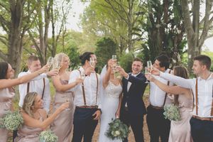 A bridal party in a toast to the bride and groom, champagne glasses raise in cheer