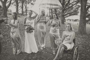 A bridal partry of ladies holding champagne glasses, boquest and umbrella in a casual setting outdoors