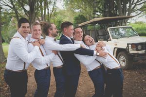 A wedding groom's party laughing and gesturing together in an outdoor background