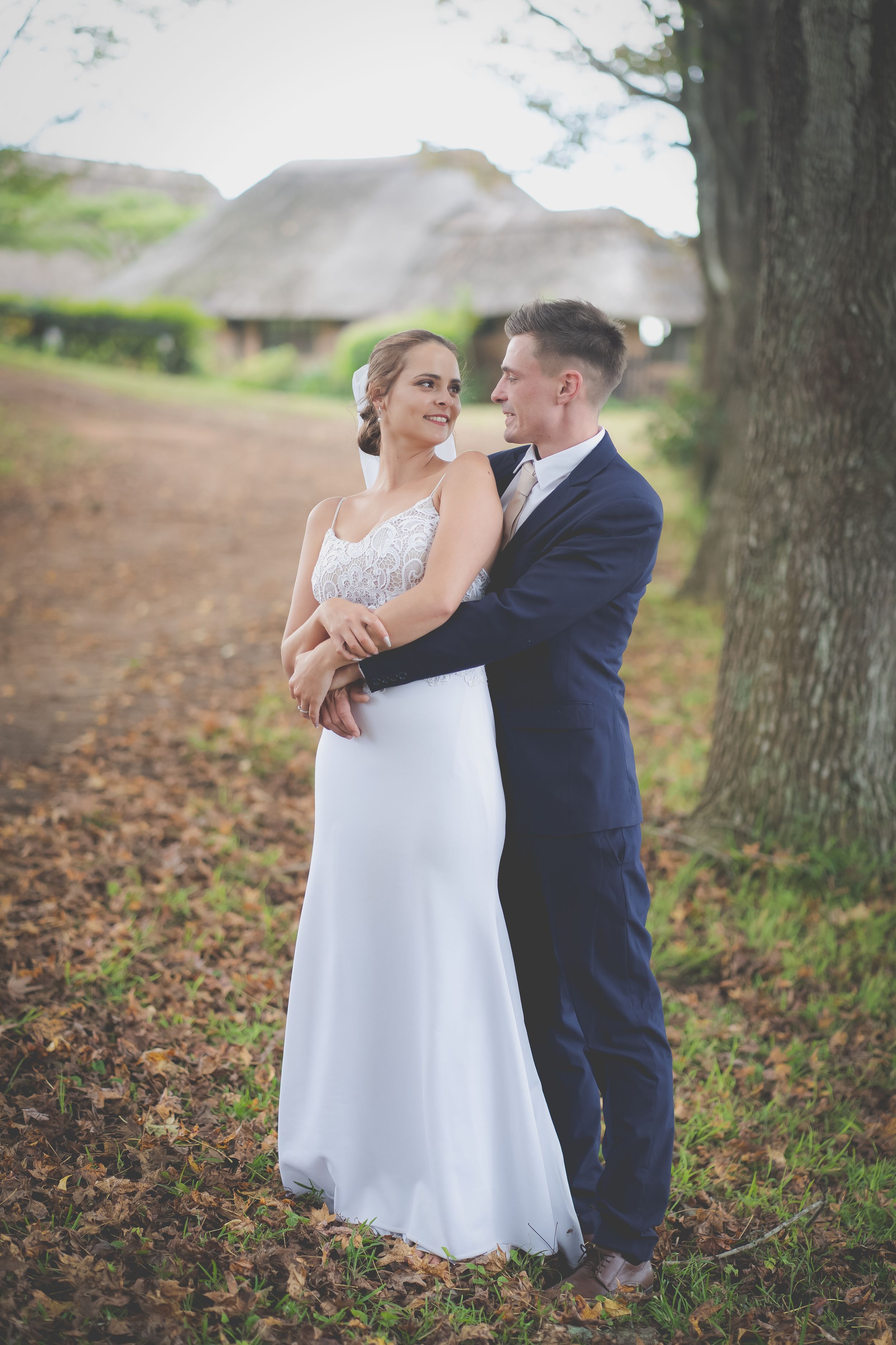A wedding couple gazing at each other with arms wrapped around one another in a garden setting