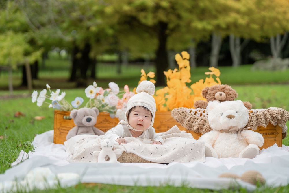 Adorable 100 days baby milestone outdoor photography with cute teddy bears, captured by a professional Auckland baby photographer.