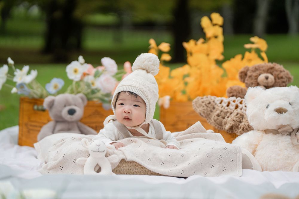 Adorable 100 days baby milestone outdoor photography with cute teddy bears, captured by a professional Auckland baby photographer.