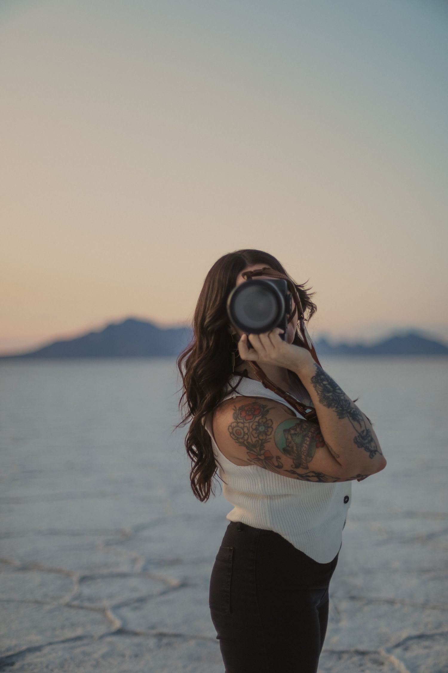 A color photo showing Lauren from Terra Firma Photography smiling with her camera on a salt flat landscape.