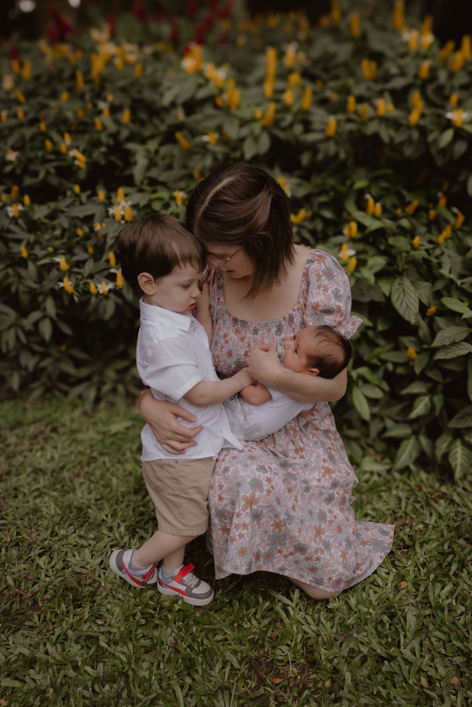 Tender family moment captured in a garden with yellow flowers blooming in the background.