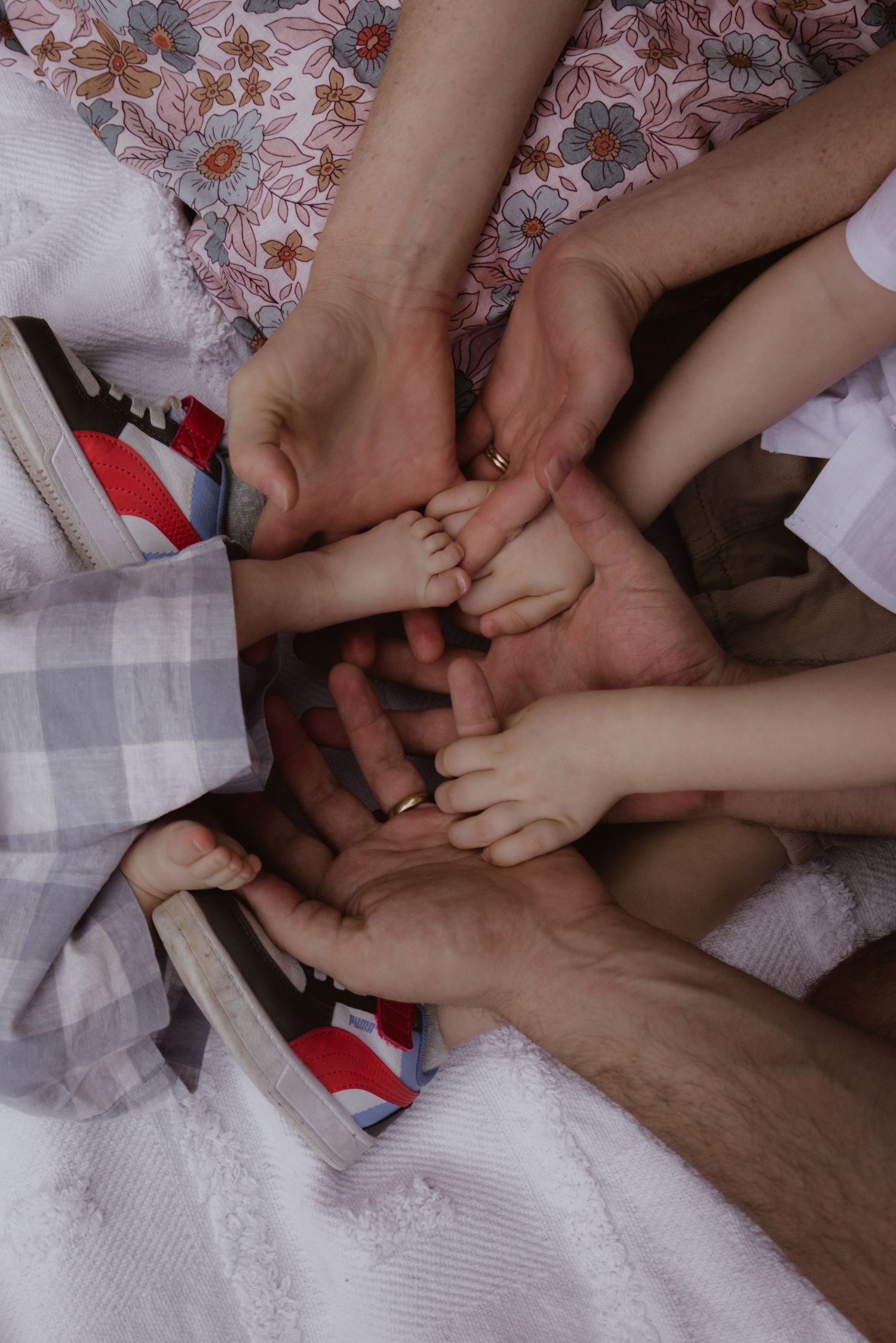 Close-up of feet and hands playing together on a white textured blanket.