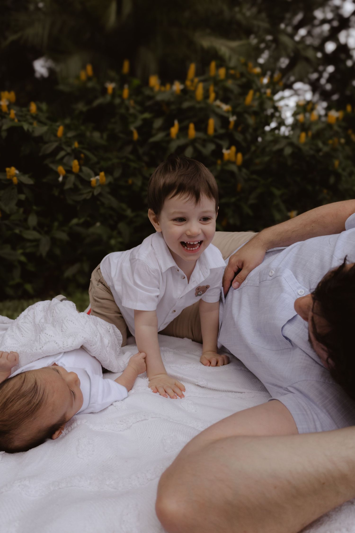 Children playing and laughing together on a white blanket in a garden setting.