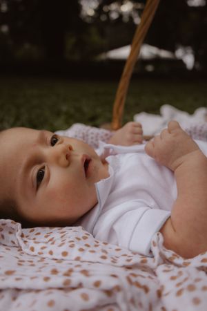 Close-up of baby lying on polka dot blanket looking up peacefully.