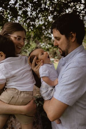 Series of intimate embraces between parent and baby in white clothing outdoors.