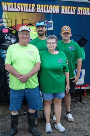 Group of people wearing green shirts standing in front of Wellsville Balloon Rally store sign.