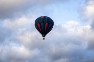 Hot air balloons floating in cloudy sky during daytime flight.