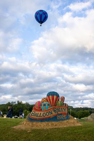 A large sand sculpture reading 'Balloon Rally 2023' with colorful hot air balloons in the sky.