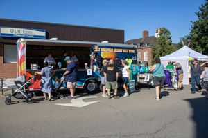 Panoramic view of outdoor market stalls and vendor tents set up in a parking lot.