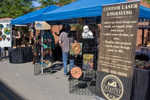 Blue canopy tent with vendor displays and merchandise racks at an outdoor market.